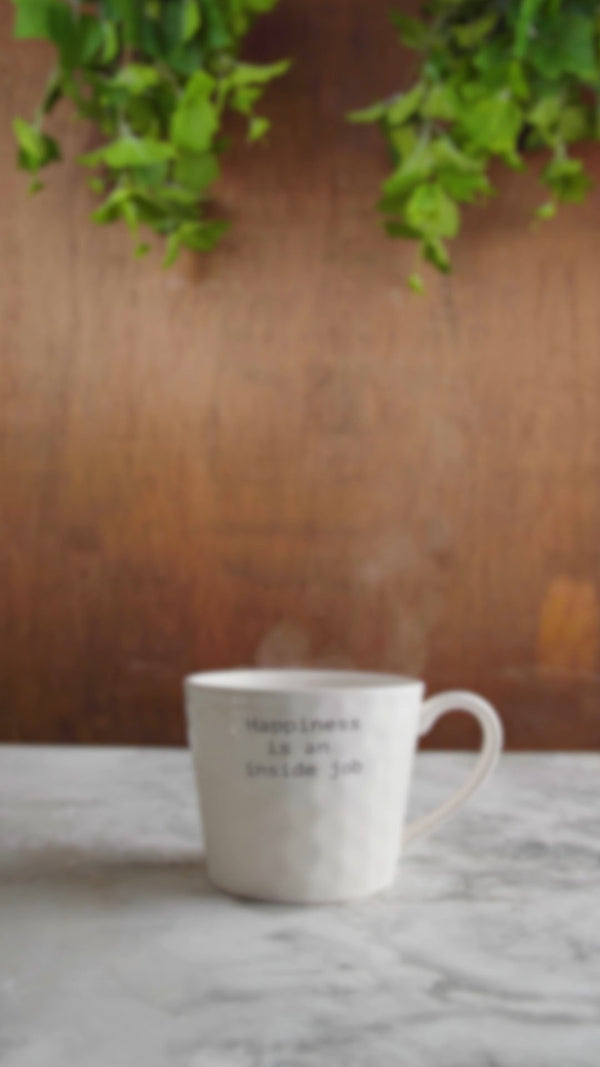 White mug with text on a marble surface with a blurred background